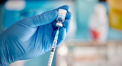 Vaccine is being drawn from a syringe.