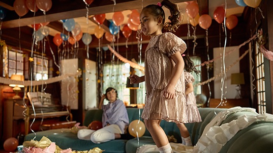 photo of a little girl jumping on the furniture at a party