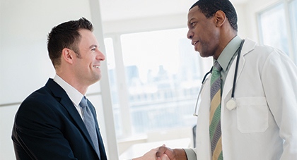 A man in a suit shaking hands with a doctor.