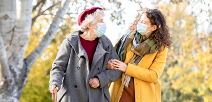 Two women wearing masks walking in the park.