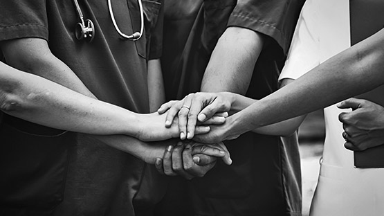 A group of AHN medical professionals doing a huddle and a hand stack together.