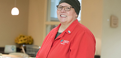 An AHN volunteer wearing a red AHN volunteer coat and smiling into the camera.