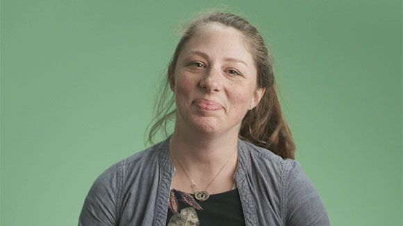 A woman smiling standing in front of a green background