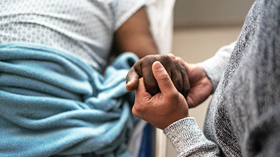 A patient and their loved ones holding hands.