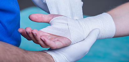 A doctor wrapping a patient's hand with a bandage.