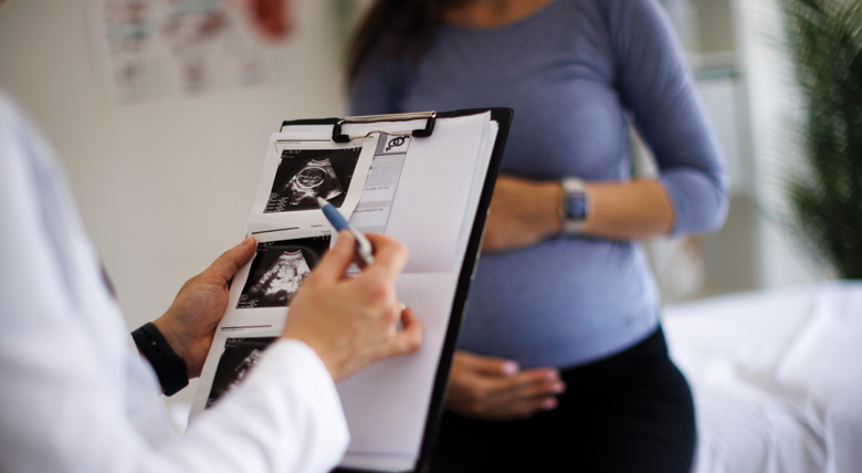 A medical professional shows ultrasound images to a pregnant person.