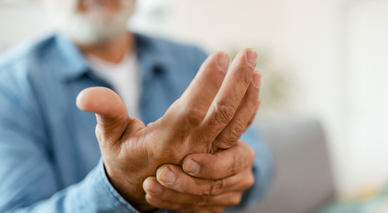 A person holds their hand like it hurts, maybe because of an autoimmune disease.