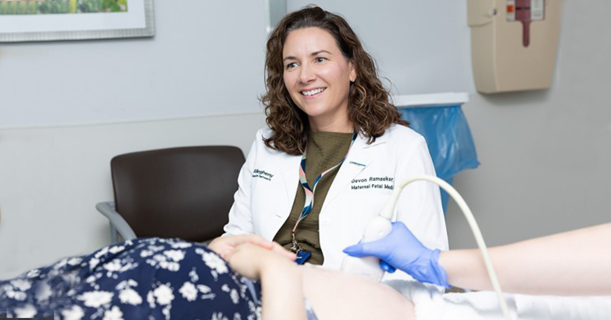 A medical professional talks to a patient while a nurse wearing blue gloves performs an ultrasound.