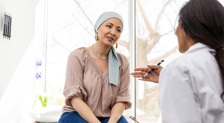 A woman wearing a headscarf smiles at a medical professional in a white coat.