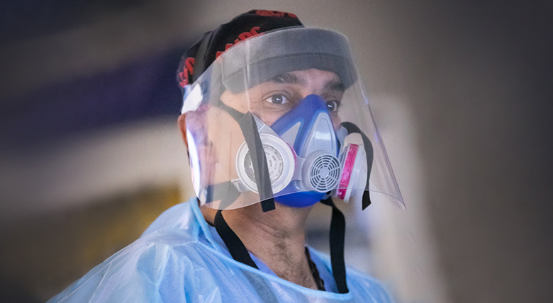 Close-up of a medical professional's face with protective gear on, focused and ready to work.