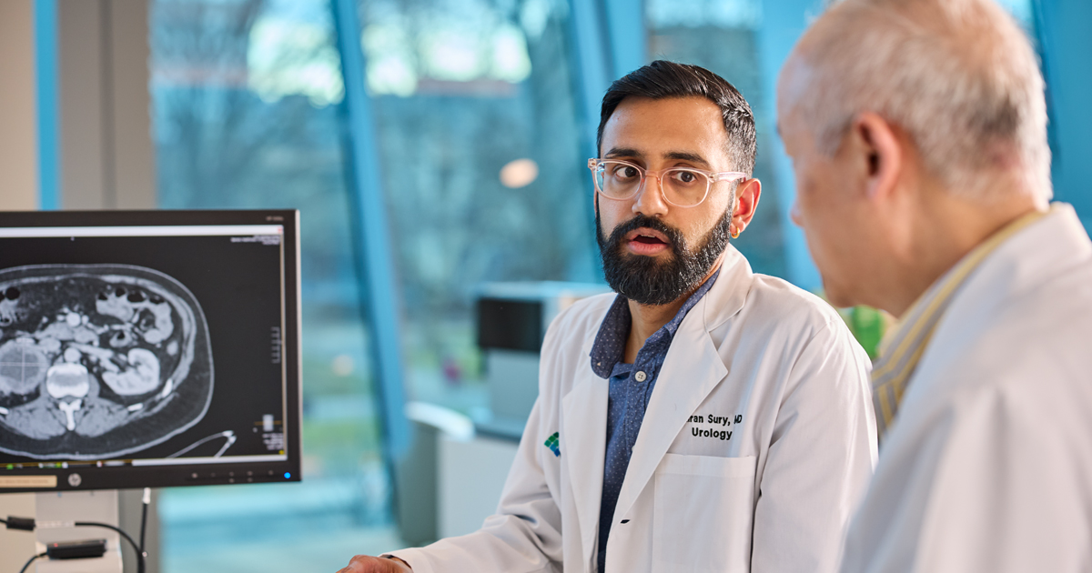 Dr. Kiran Sury is talking with another physician with diagnostic imaging in the background.