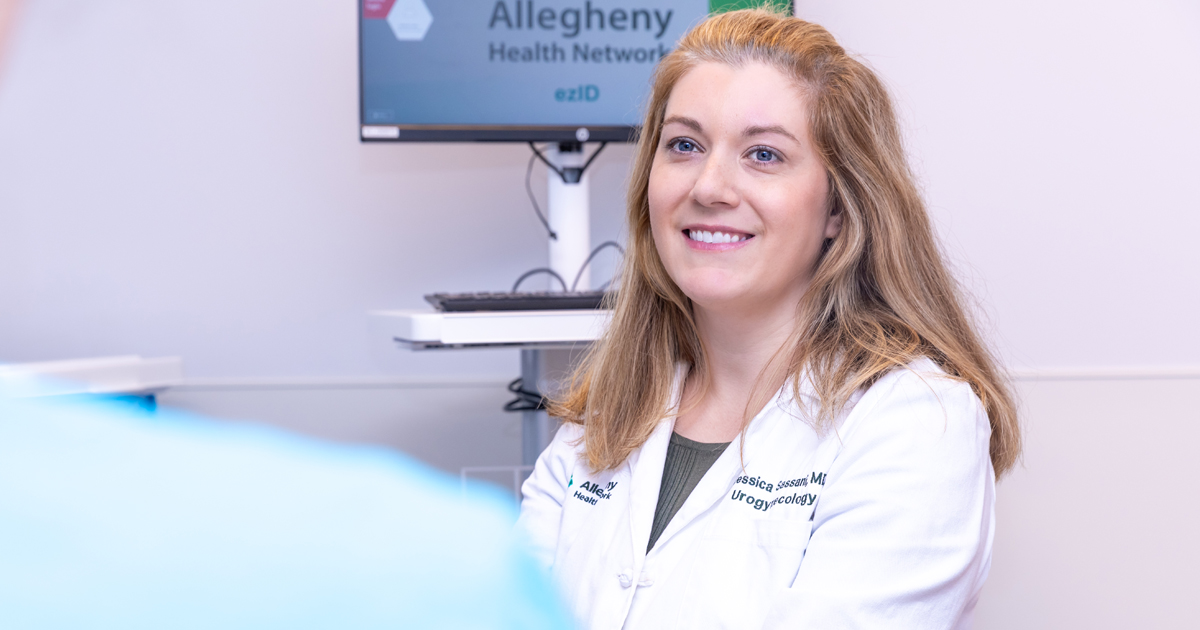 Dr. Jessica Sassani is smiling in a white lab coat in a clinical setting.