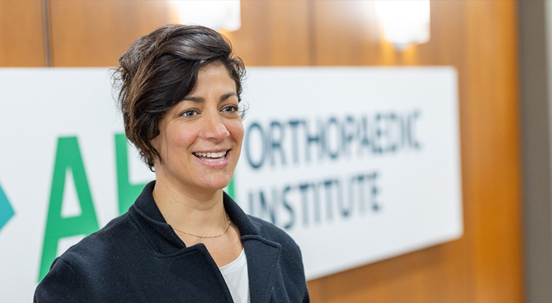 Close up of a Hispanic medical professional smiling in front of the Orthopedic Institute sign.
