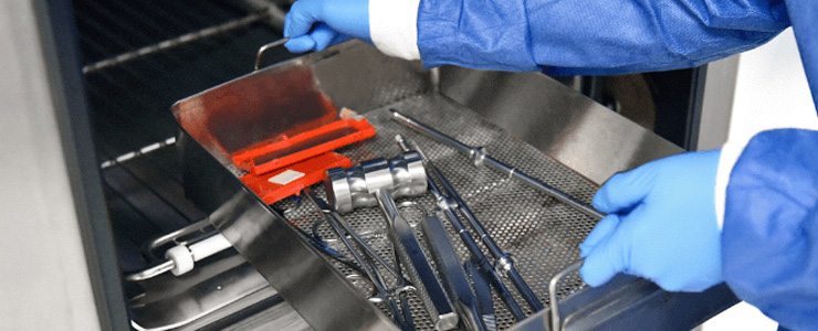 image of lab technician placing medical instruments in washer