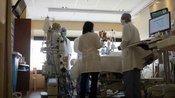 Cardiology fellows huddled around a heart failure patient's hospital bed.