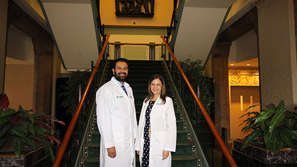 2016-2017 graduates Rikinder Sandhu, MD and Monika Murillo, MD standing next to each other in front of a staircase.