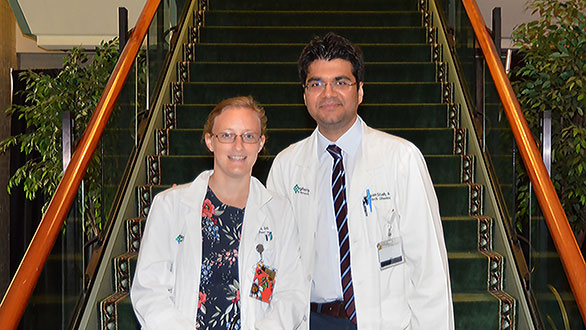 2017-2018 graduates Holly Bean, DO and Arpan Shah, MD standing next to each other in front of a staircase.