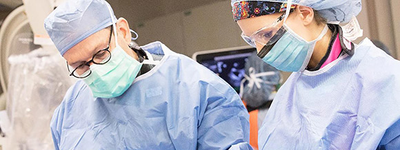 image of 2 doctors wearing masks and surgical gowns performing surgery