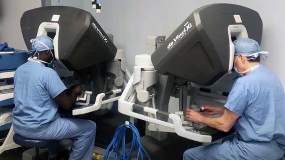 Two general surgery residents, one black and one white, practice using the Da Vinci robotic surgical system.