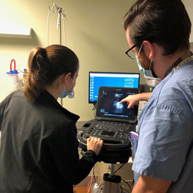 Two residents wearing masks in simulation lab enhancing their skills. 