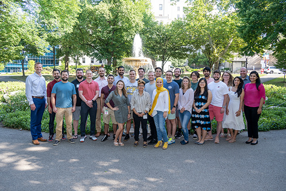 a group shot of radiology residents in a park with a fountain 