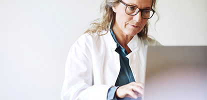 Physician researching information into a laptop computer