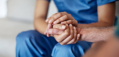 A nurse holding a patient's hand.