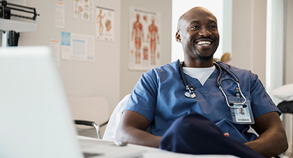 A nurse sitting in front of a computer smiling.