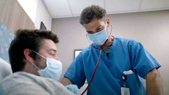 Doctor checking the heartbeat of a patient with a stethoscope in an exam room