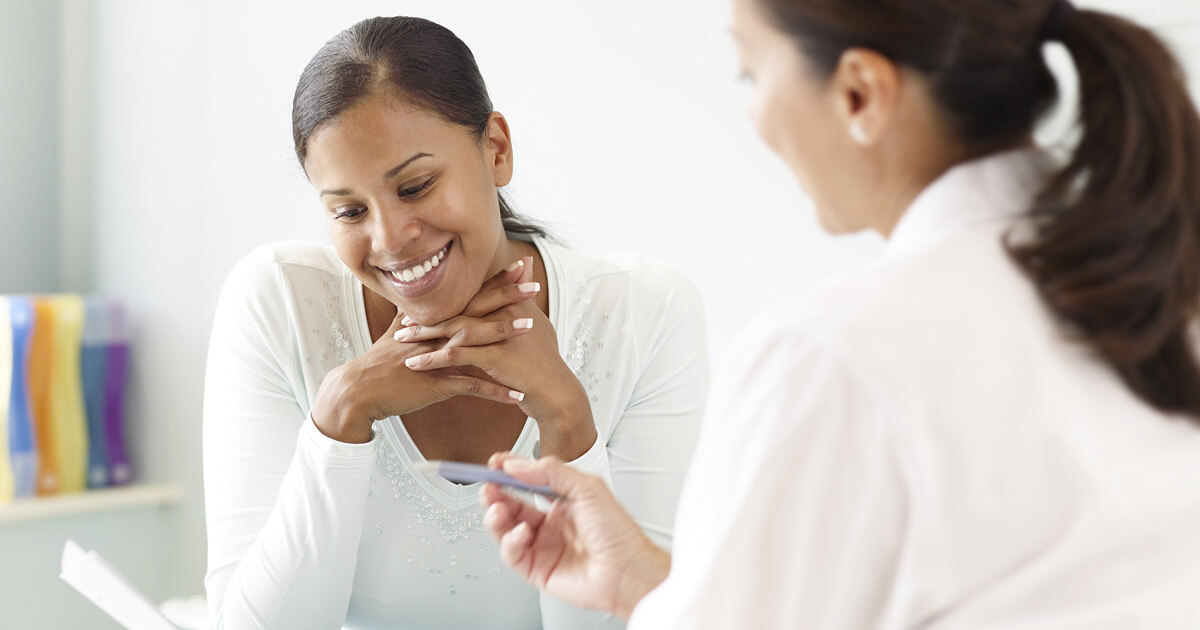 Female healthcare professional talks with adult female patient in office.