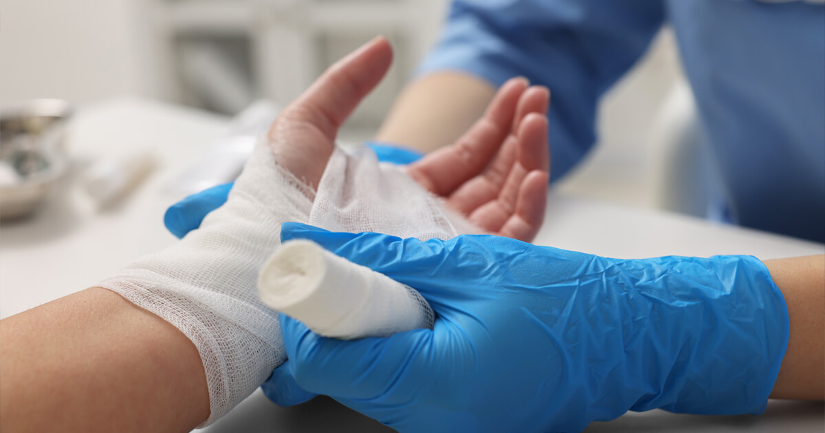 Hand being bandaged by a medical professional in sterile gloves