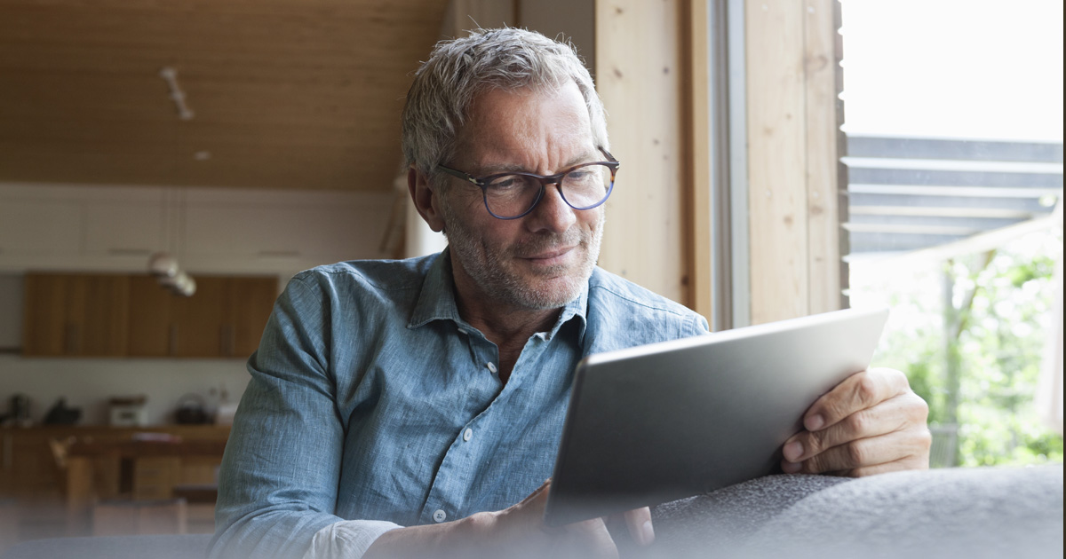An older white man with gray hair uses a tablet.