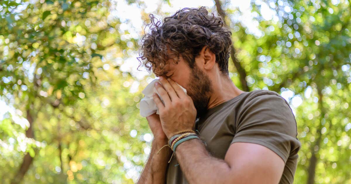 Man sneezing while outdoors