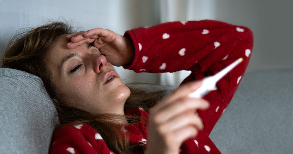 Sick woman looking at thermometer
