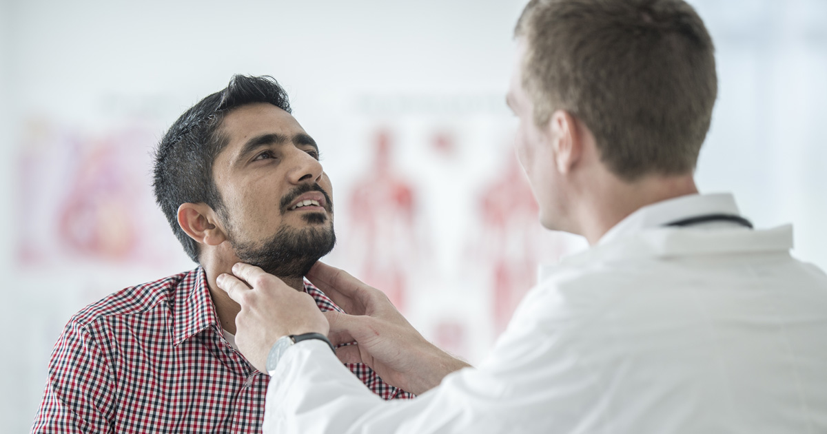A medical professional checks a man's throat in a doctor's office.