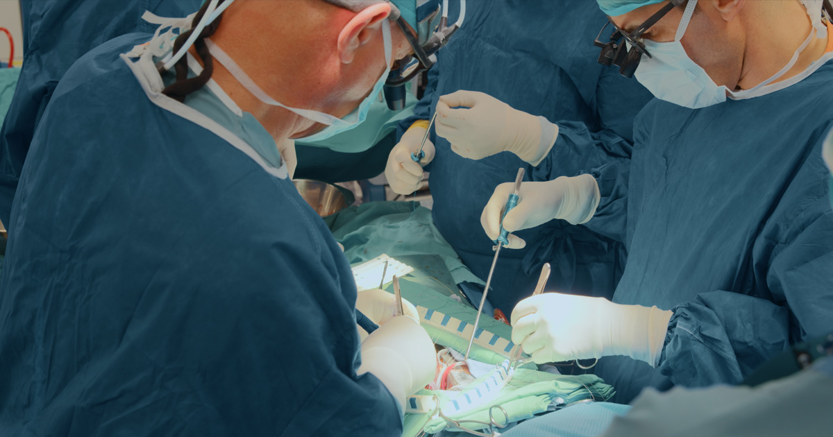 Group of surgeons gathered around operating table doing a procedure
