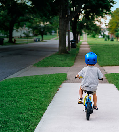  little boy riding bicycle down sidewalk