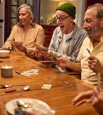 a group of adults enjoying playing a card came around a table