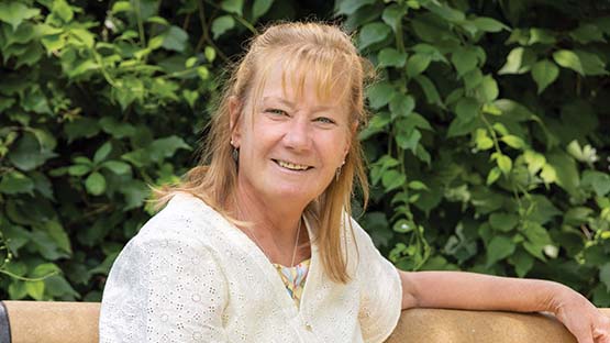 AHN patient Michele Allison sitting on a bench and smiling into the camera.