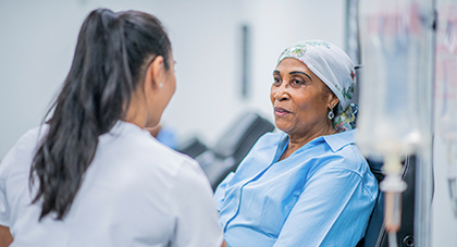 A nurse talking to an older cancer patient during treatment.