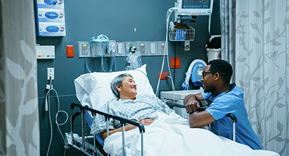 A nurse talking to a patient laying in an ER hospital bed.
