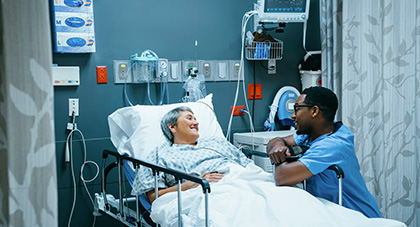 A nurse talking to a patient laying in an ER hospital bed.