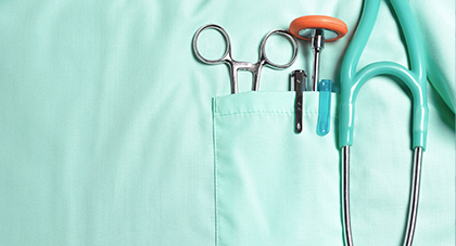 A close up of a physician’s scrubs pocket with a stethoscope and other surgery tools in it.
