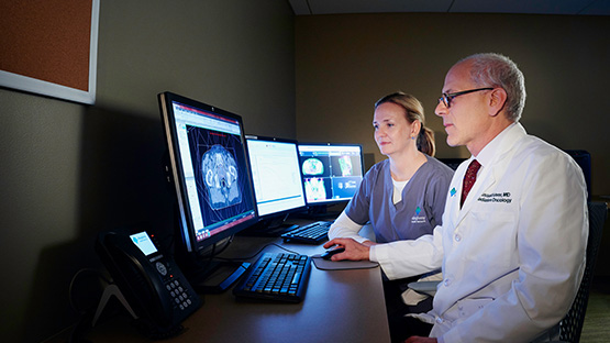 Two AHN physicians reviewing a patient’s scans on a computer.