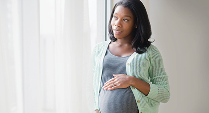 pregnant woman looking thoughtfully out a window