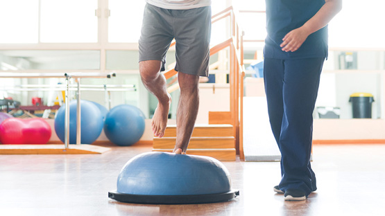 A personal trainer working with a patient to improve his balance.