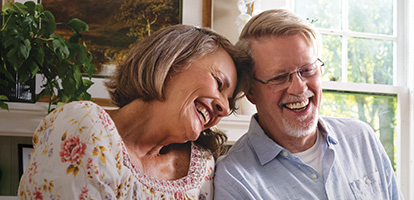 A man and woman smiling and leaning against each other