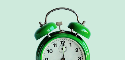 A green alarm clock that is about to go off.