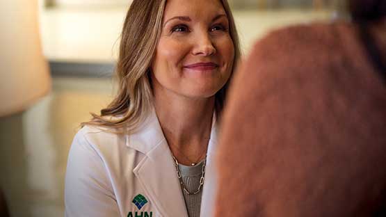 A doctor in a lab coat looking up smiling at a patient