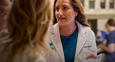 A doctor in a lab coat talking to patients